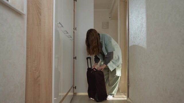 Unwind post travel. Woman arranges household items carefully. She accommodates herself after overseas venture. Revisiting her residence and confirming proper arrangement of items