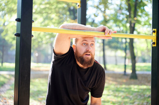 White man watching yellow sign. Bearded male with bright eyes examining park activity attentively. Whitebearded man standing in observation stance near yellow alert sign in park scenario
