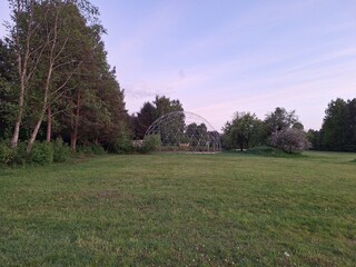 Fototapeta premium Dome structure stands in an open field surrounded by trees during twilight