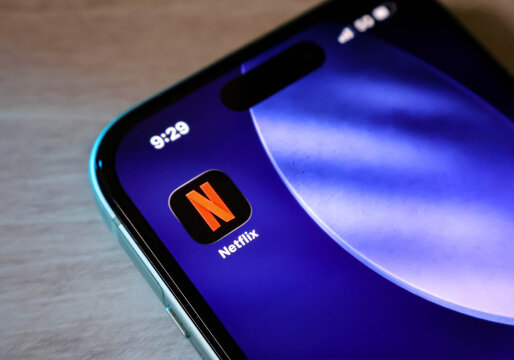 Closeup of a smartphone screen showing the netflix app icon on a blue abstract background with a 5g signal indicator and time display