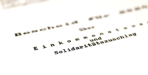 Fototapeta premium Close-up of a German tax certificate (Einkommensteuer), a document used to determine income tax refunds or additional payments. Tax office, application, allowance, tax return for individuals.
