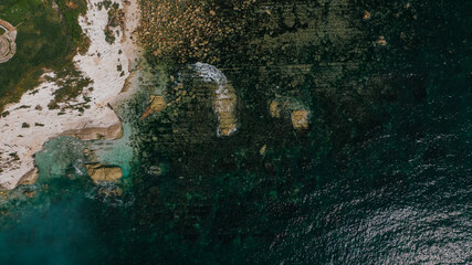Aerial top down view of a rocky coastline and clear turquoise sea © Reuben