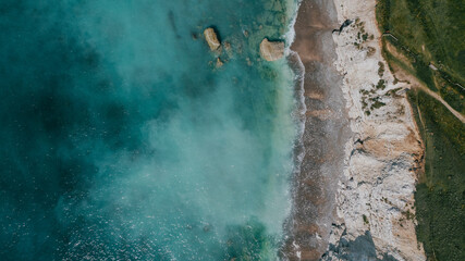 Aerial top-down view of turquoise sea and white chalk cliffs © Reuben