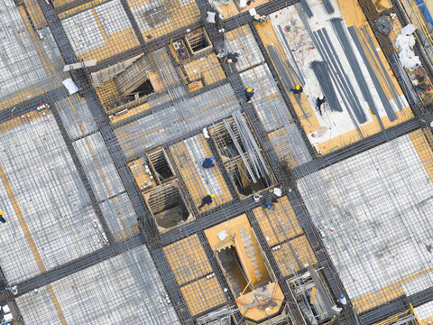 Aerial view of a construction site with workers installing rebar grids and steel reinforcement on a building foundation Taiwan.