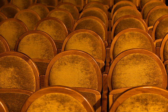 Rows of empty wooden velvet seats in theater or concert hall