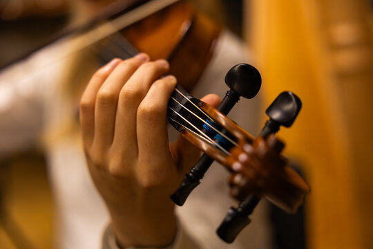 Close up of child hand playing violin during classical orchestra concert
