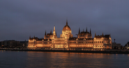 Naklejka premium View from Buda Embankment of Parliament building illuminated by a floodlights on Pest embankment in Budapest in Hungary