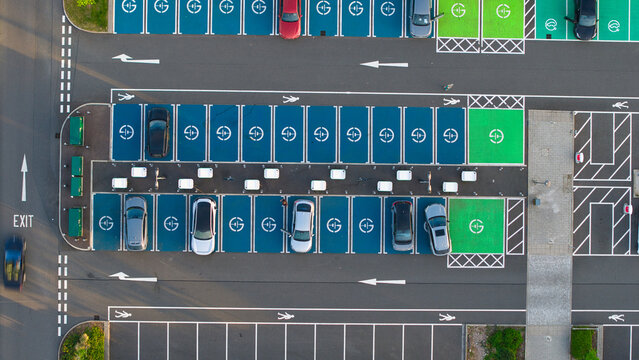 Aerial view of the electric vehicle charging station at Rugby Services with cars parked in blue and green bays and white charging units Rugby, England, United Kingdom.