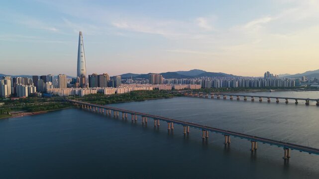 Aerial parallax around Jamsil Railway Bridge with Lotte World Tower and Songpa District skyline over Han River at golden hour in Seoul South Korea