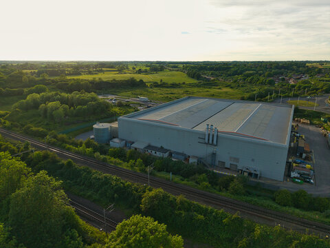 Aerial view of the Rugby Cement Plant industrial facility surrounded by railway tracks and green fields under a hazy sky in Rugby, England, United Kingdom.