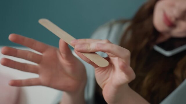 Woman manicures nails. Woman carefully caring for nails. Young woman diligently grooming her nails during routine care. Woman attentively tending to her nails as part of personal grooming routine