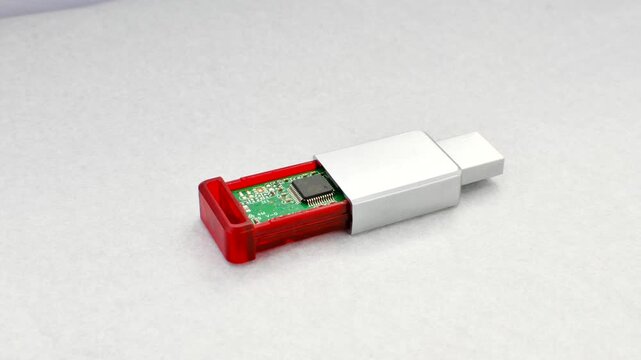 Close-up of a disassembled USB flash drive on a white background, revealing its internal complexity. Close-up of an open USB flash drive, exposing circuits and connections, on a white surface.
