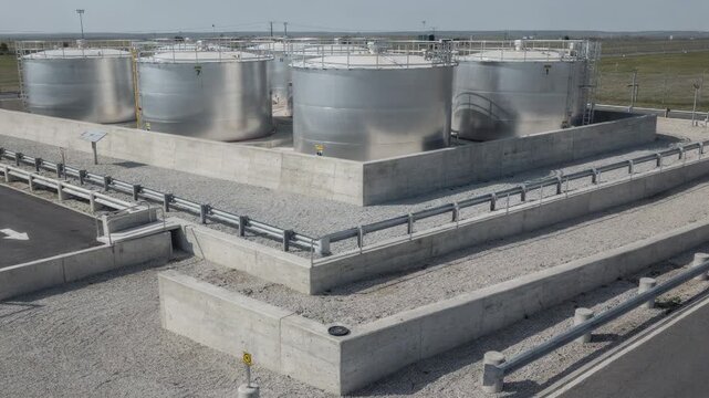 Doublewall storage tanks housed within a tank farm protected by concrete dikes and perimeter barriers emphasizing environmental containment and hazard prevention.