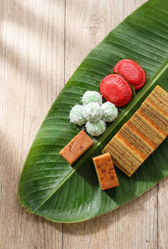 Authentic Indonesian traditional snacks, jajanan pasar, served neatly on a fresh banana leaf with soft morning sunlight shadows.