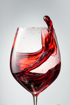 Wine glass with red liquid frozen in movement.