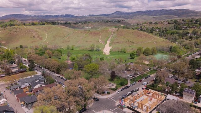 Slow push-in drone shot from high altitude in wide angle over Camel's Back Park, Boise, Idaho. Camera facing north reveals the full park, hills, and city views on a sunny day.