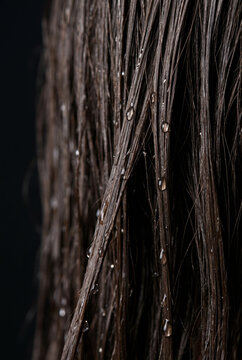 Wet brown hair close up with water drops strands texture shampoo conditioner haircare beauty concept dark background