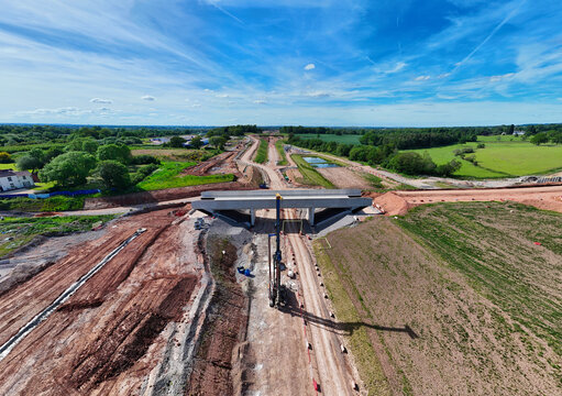 Aerial view of HS2 Civil Engineering Works featuring a concrete bridge structure, heavy machinery, and excavated earth surrounded by green fields Balsall Common, England, United Kingdom.