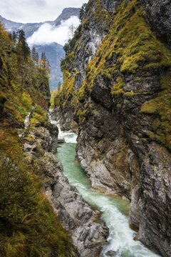 The river Lammer in the gorge Lammerklamm (Lammer&ouml;fen) . A path leads through the gorge on the left. In the background the Hohe Br&uuml;cke, a footbridge over the gorge. The Tennengebirge mountains in the far background. Autumn. Scheffau, Lammertal, Salzburger Land, Upper Austria, Austria