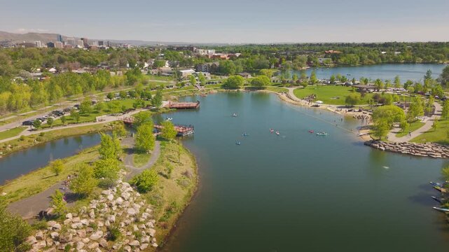 High altitude drone shot of paddleboards and swimmers playing near the piers in Esther's Pond at Esther Simplot Park, Boise, Idaho. Sunny day recreation on the calm water.
