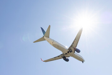 Fototapeta premium A passenger airplane flying in a clear blue sky. View of the airplane from below showing its underside.