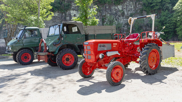Roter Traktor von Fahr vor zwei alten Unimogs auf einer Ausstellung in Schuld, Deutschland, 23.05.2026
