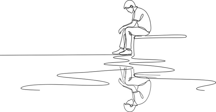 Sad boy sitting alone, looking down, with reflection in water