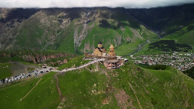 Ancient stone church building on green mountain peak ridge aerial view.
