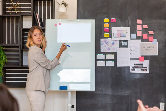 Person presenting at a whiteboard in a modern office setting.