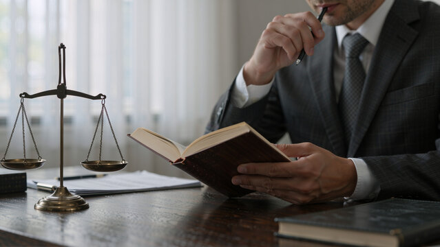 Lawyer reading a book next to scales of justice