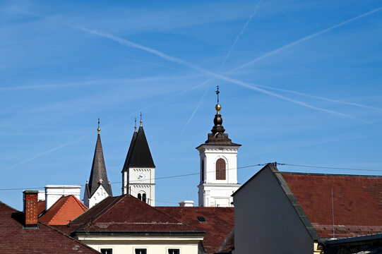 church towers in elevation view in the city of Veszprem in Hungary. white stucco exterior wall finish. steep sloped roofs. Christian cross on top. travel, tourism, architecture and religion concept 