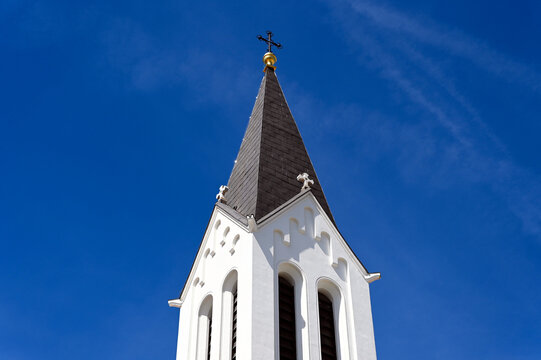 church bell tower. low angle elevation. the city of Veszprem, Hungary. white stucco exterior wall finish. steep sloped roof. Christian cross on top. travel, tourism, architecture and religion concept