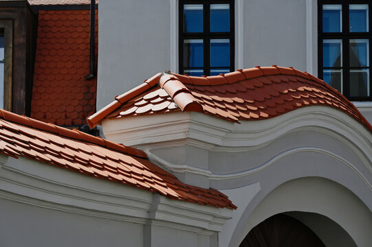 beavertail clay tile sloped residential roofs. bright shiny new copper plated roof dormers. new construction. closeup view. reflective glass window. mansard roof. modern house architecture.