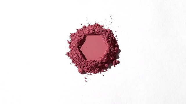 Orbiting capture of a pile of red powder with a clear hexagonal impression on a light gray backdrop lit with dynamic orbiting light casting shifting shadows | Concept for blush commercial