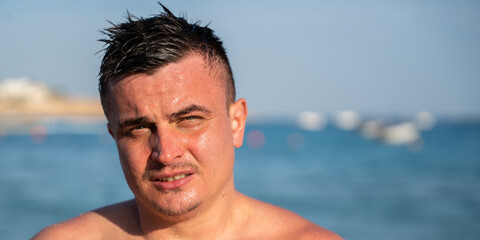 Wet caucasian man stands near the sea in Sharm El Sheikh Egypt with sunlight on his face and blurred beach background. Summer vacation and active lifestyle © timoha.ig
