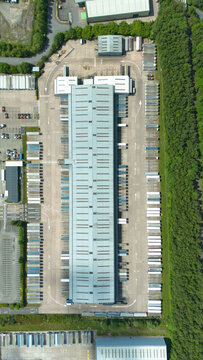 Aerial view of a large logistics warehouse featuring rows of semi-trailers at loading bays and extensive parking facilities Kingsbury, England, United Kingdom.