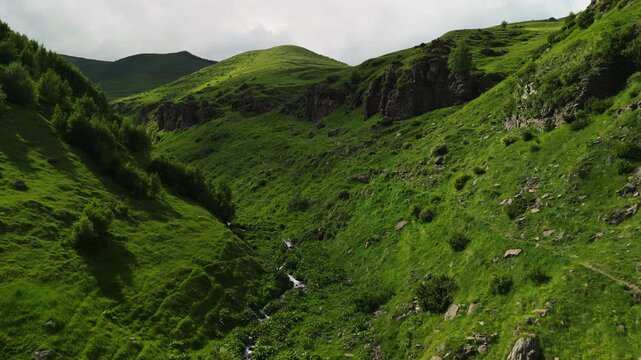 Epic Gergeti canyon mountain river valley aerial flight. 
Cinematic drone forward tracking shot inside deep gorge 
along wild stream near Kazbegi historic church in Georgia.

