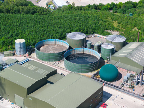 Aerial view of the Biogen Atherstone anaerobic digestion plant with large circular storage tanks and industrial buildings near green woodland Atherstone, England, United Kingdom.