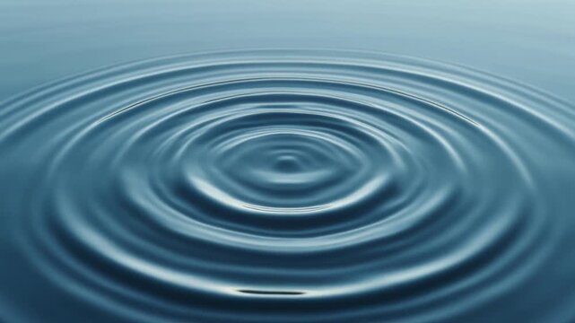 Mesmerizing concentric ripples gently expand across a tranquil blue water surface, creating a captivating and serene visual pattern