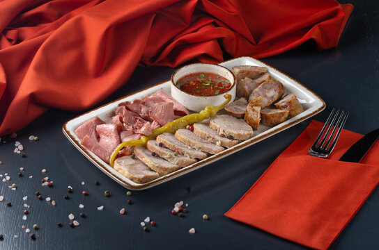 meat plateau dry-cured meat, baked boiled pork, carpaccio, sausage On a dark background