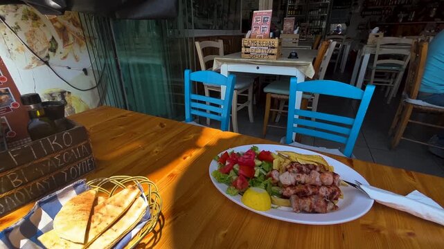 A table at a restaurant. Greek menu - pork souvlaki, vegetables, pita, French fries. Grilled meat in Cyprus.