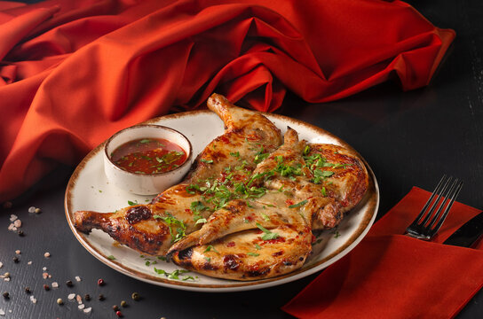 Georgian cuisine dish chicken tapaka or tabaka on a plate, on wooden background. Grilled chicken. close up