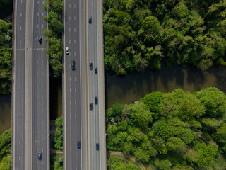 Motorway bridge with black cars crossing the river aerial top down view. Beautiful lush green environment with trees by the river Medway. Light traffic on M20 motorway in Kent, UK. © Ssisabal