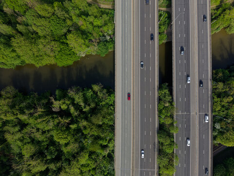 Motorway bridge with traffic crossing the river aerial top down view. Beautiful lush green environment with trees by the river Medway. Light traffic on M20 motorway in Kent, UK.