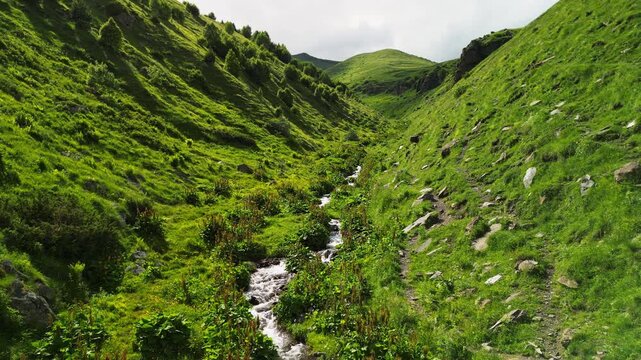Epic Gergeti canyon mountain river valley aerial flight. 
Cinematic drone forward tracking shot inside deep gorge 
along wild stream near Kazbegi historic church in Georgia.
