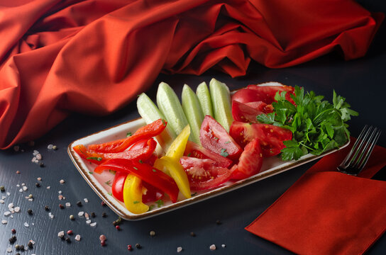 Assorted vegetables in a plate. Slicing fresh vegetables: cucumber, tomato, pepper. Restaurant menu.