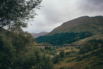 Naklejka premium The historic Glenfinnan Viaduct surrounded by lush green hills, Scottish Highlands