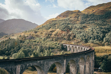 Naklejka premium The historic Glenfinnan Viaduct surrounded by lush green hills, Scottish Highlands