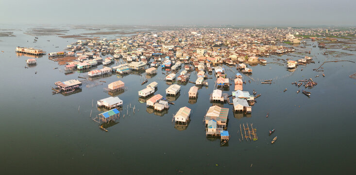 Aerial view of the stilt village with wooden houses built over Lake Nokoue and local boats with people navigating the calm waters of Ganvie, Atlantique, Benin.
