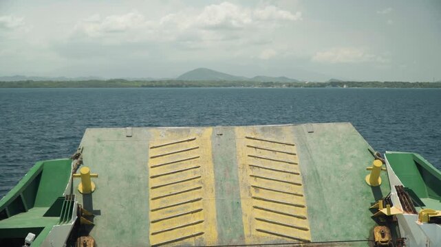 Ferry ramp center, open sea view symmetrical yellow plates lowered for loading, twin bollards and rusted metal textures, port coastline under cloudy sky, commercial vehicle crossing vibe, departure